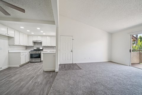 A spacious kitchen with white cabinets and a grey rug on the floor.