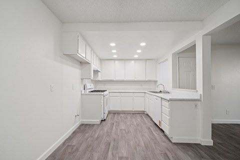 A kitchen with white cabinets and a wooden floor.