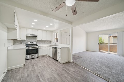 A spacious kitchen with white cabinets and a grey floor.