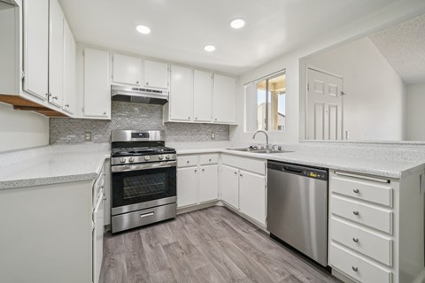 A modern kitchen with white cabinets and stainless steel appliances.