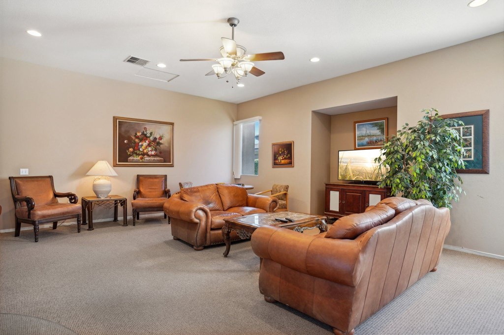 a living room with couches and chairs and a ceiling fan