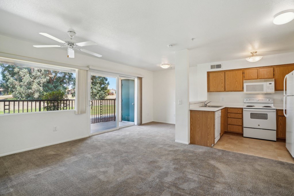 an empty living room with a kitchen and a large window