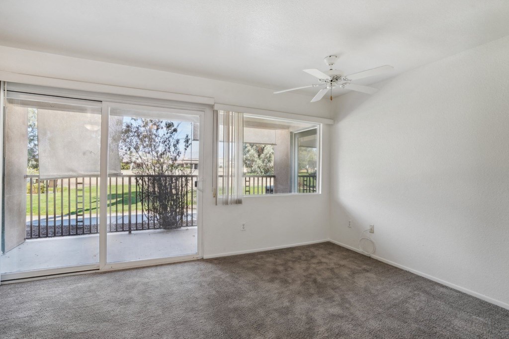 an empty living room with sliding glass doors and a ceiling fan