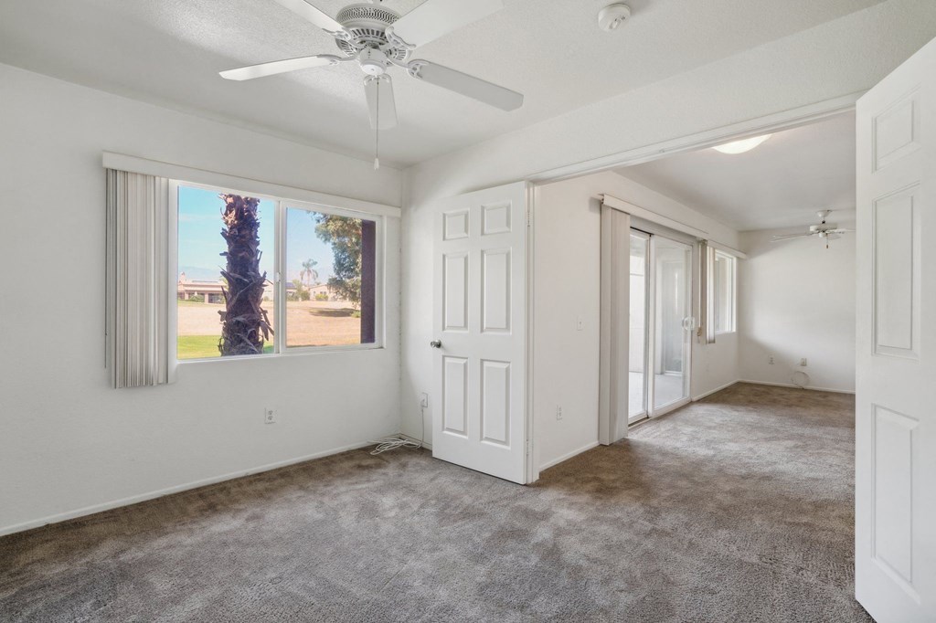 an empty living room with a ceiling fan and a window