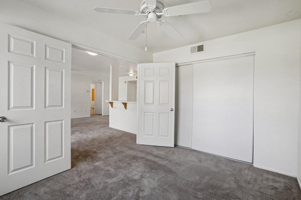 an empty room with white walls and a ceiling fan