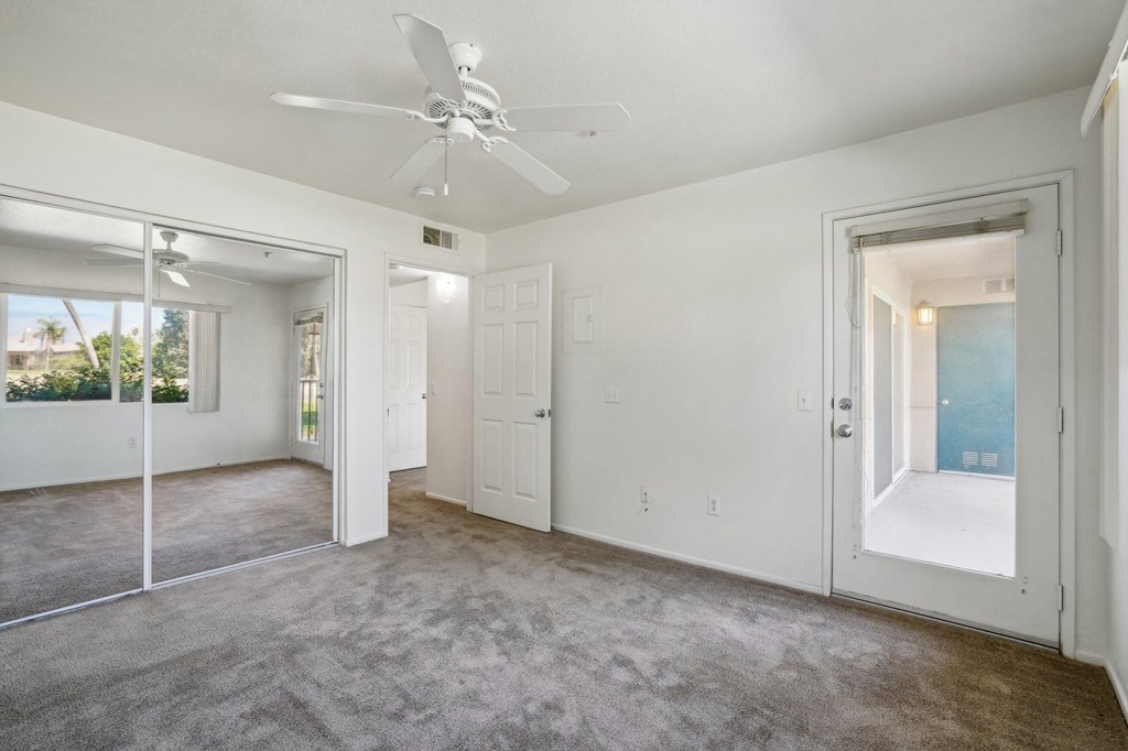 an empty living room with white walls and a ceiling fan