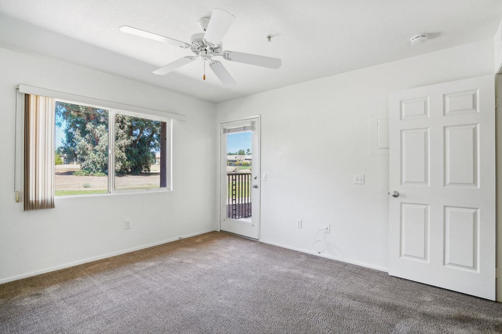 an empty living room with white walls and a ceiling fan