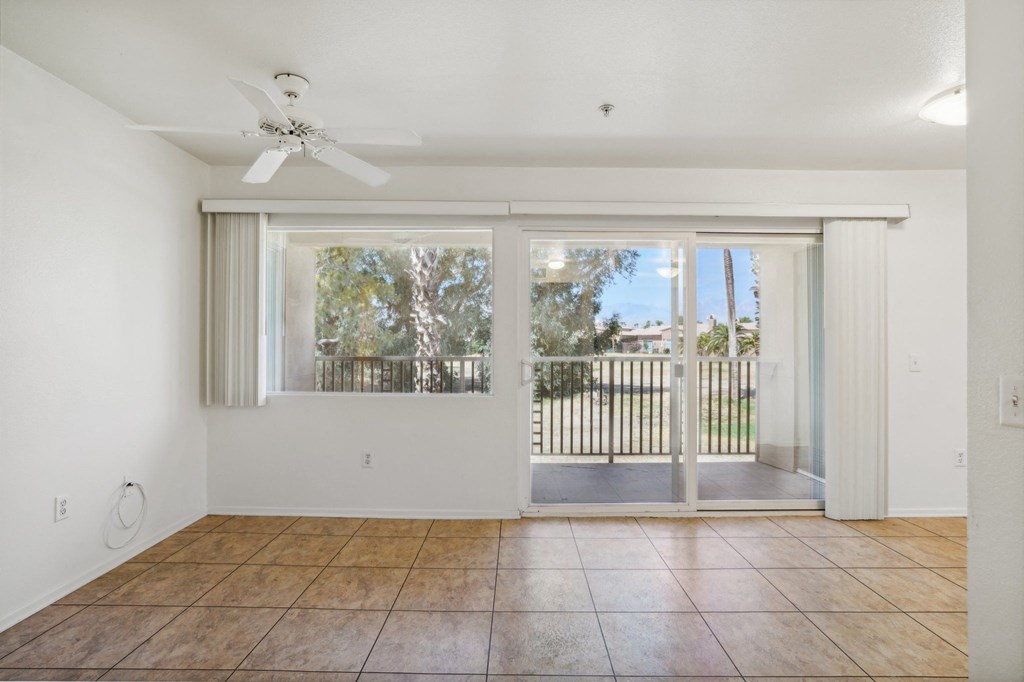 an empty living room with a sliding glass door to a balcony