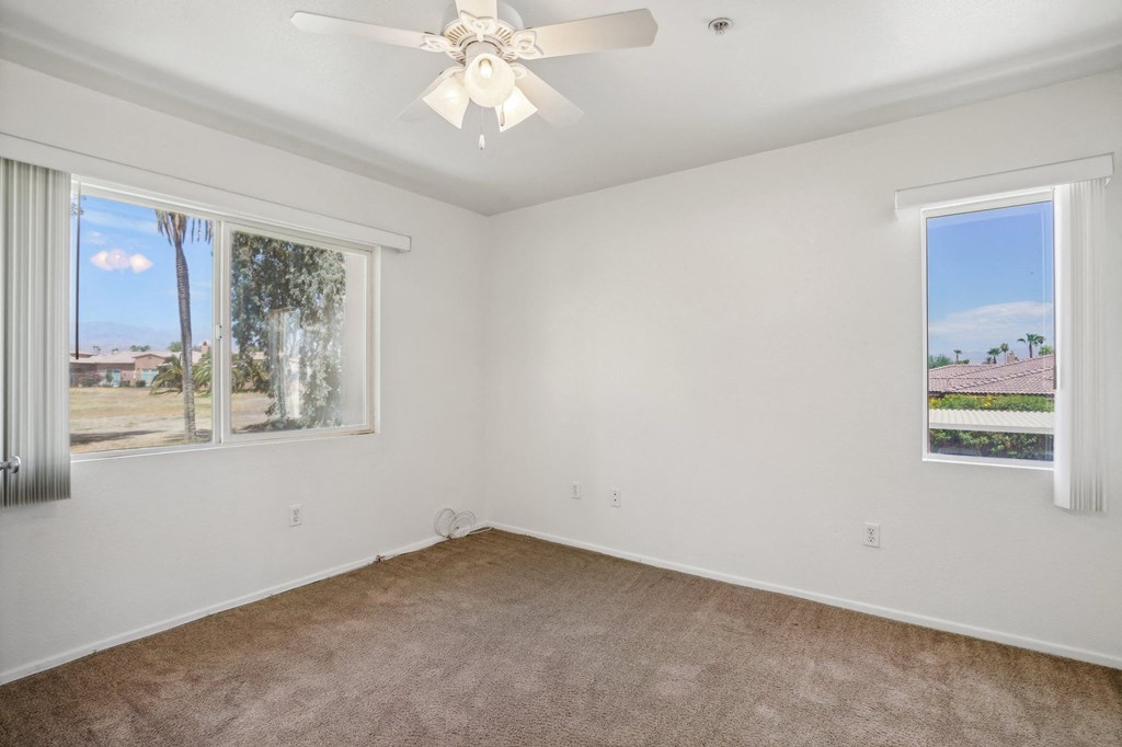 an empty living room with a ceiling fan and a window