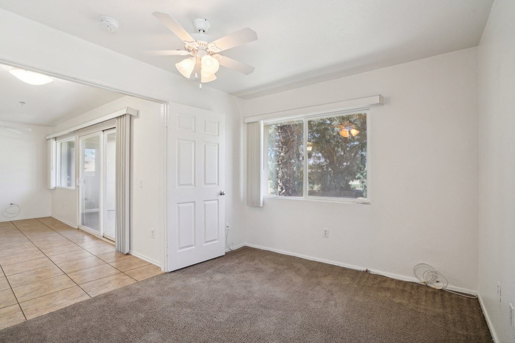 an empty living room with a ceiling fan and a window