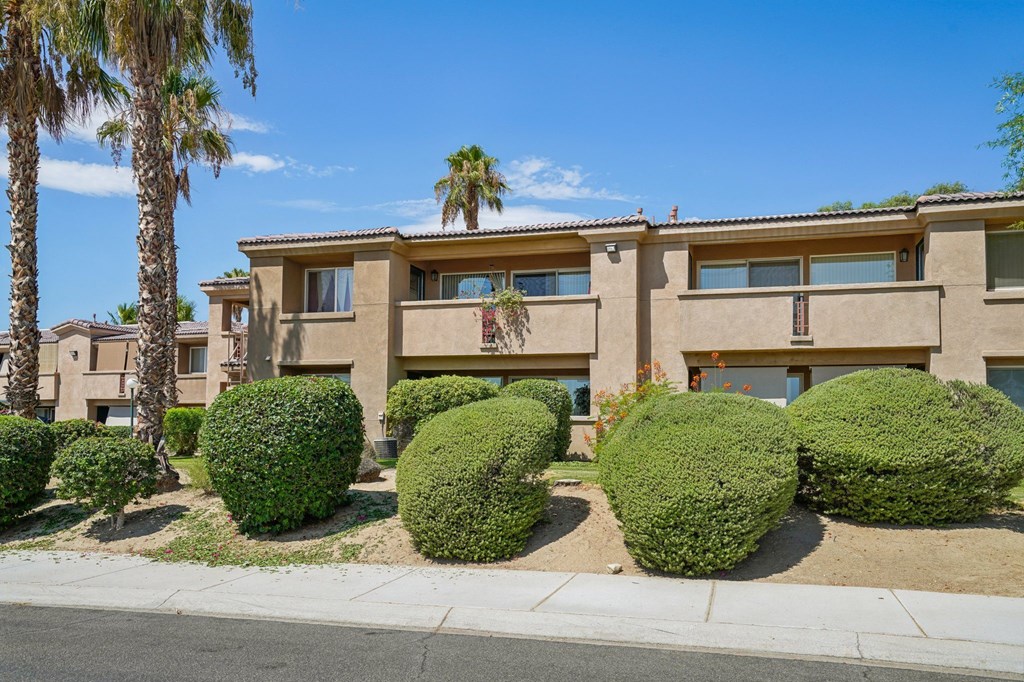 a building with bushes and palm trees in front of it