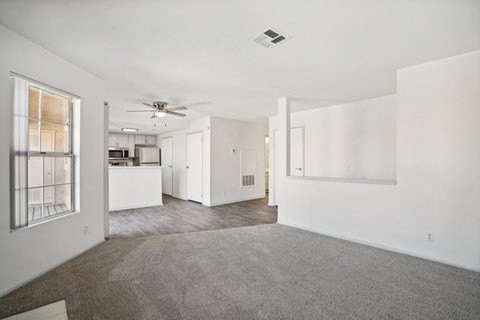 an empty living room with white walls and a kitchen