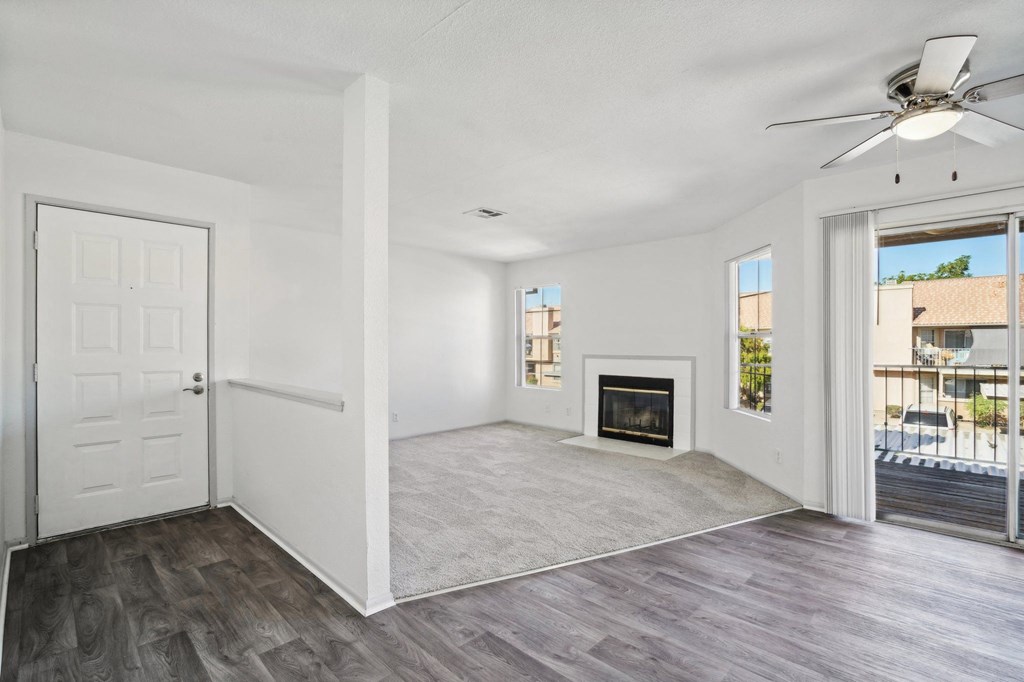an empty living room with a fireplace and a ceiling fan