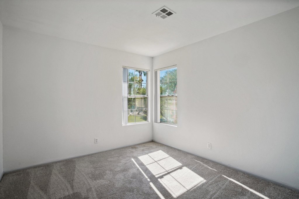 an empty room with white walls and two windows