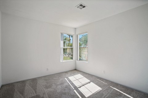 an empty room with white walls and two windows