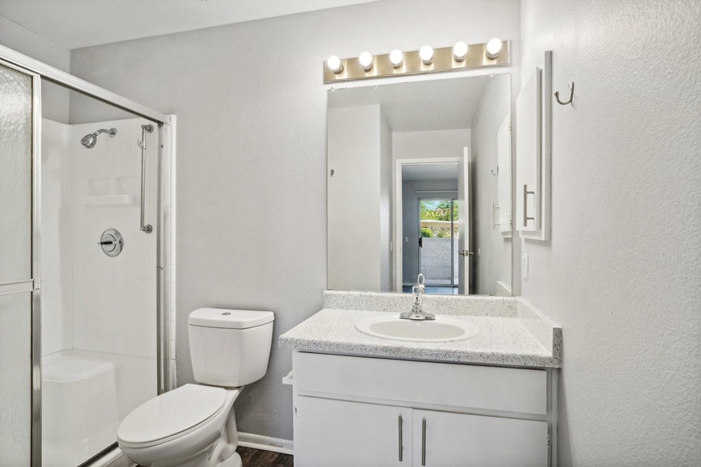 A white bathroom with a toilet, sink, and mirror.