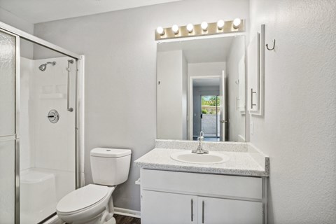A white bathroom with a toilet, sink, and mirror.