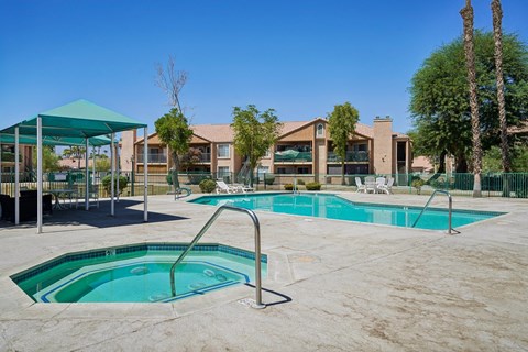 A swimming pool area with a green canopy and a building in the background.
