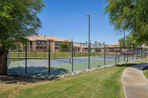 A tennis court surrounded by a fence and trees.