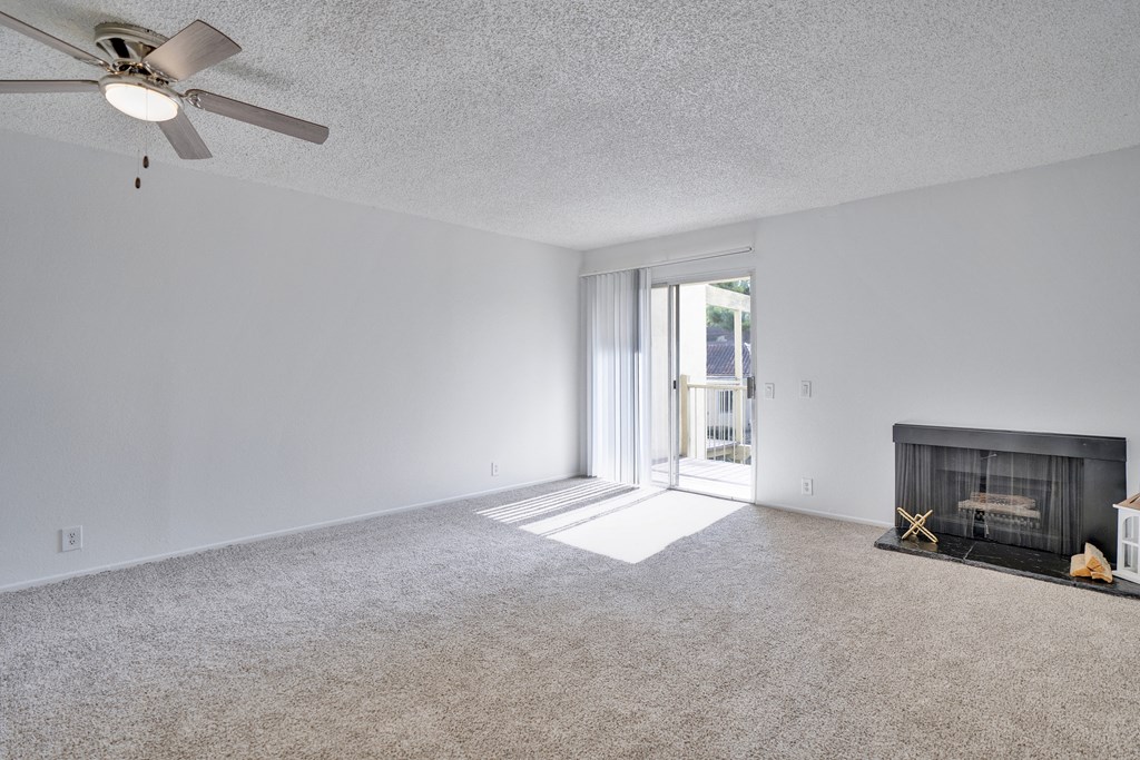 A living room with a fireplace and a ceiling fan.