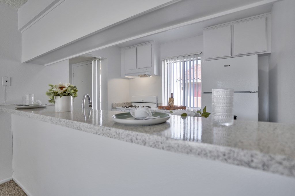 A white kitchen with a marble countertop and modern appliances.