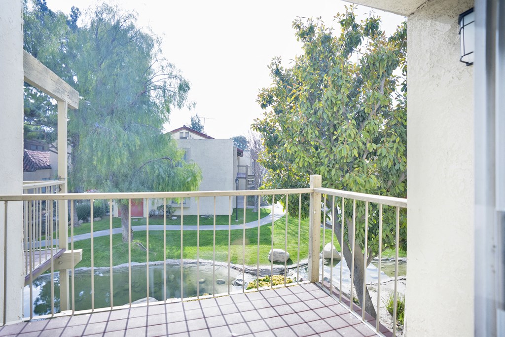 A balcony with a view of a garden and a house.