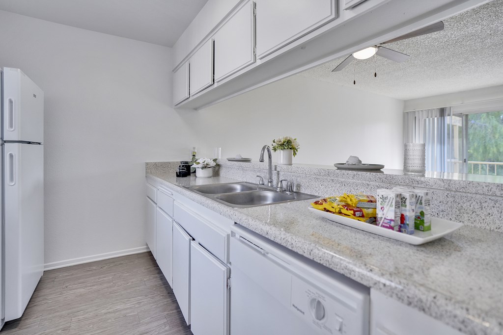 A kitchen with white cabinets and a white fridge.