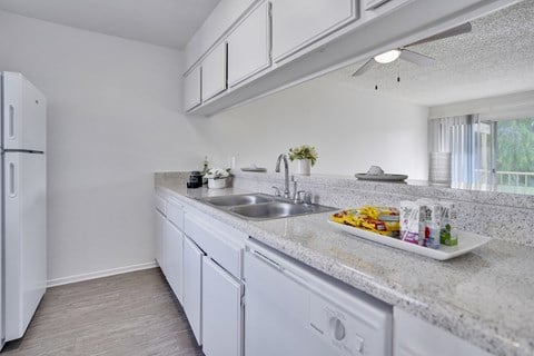 A kitchen with white cabinets and a white fridge.