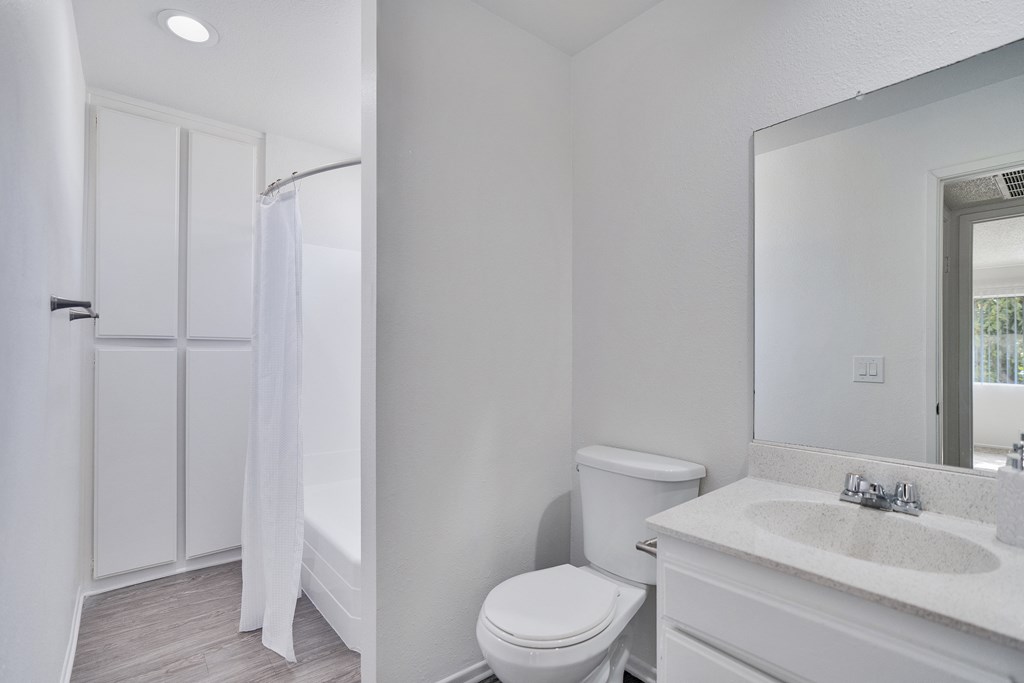 A white bathroom with a toilet, sink, and shower.