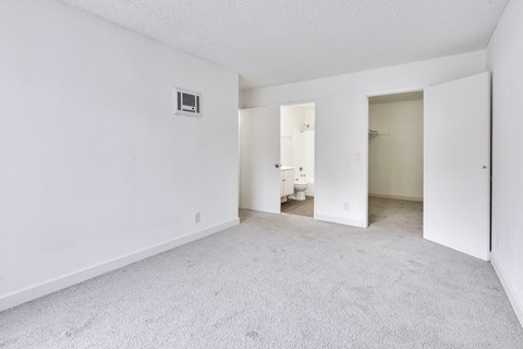 A white room with a carpeted floor and a doorway leading to another room.