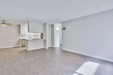 A room with a ceiling fan and a kitchenette.