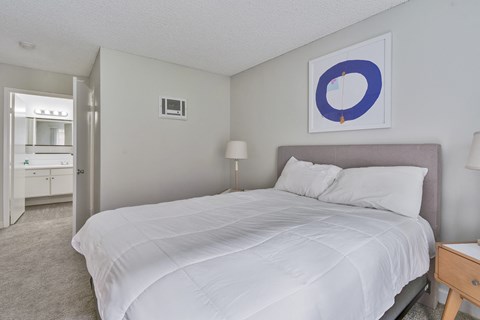 A bedroom with a large bed and a painting on the wall.