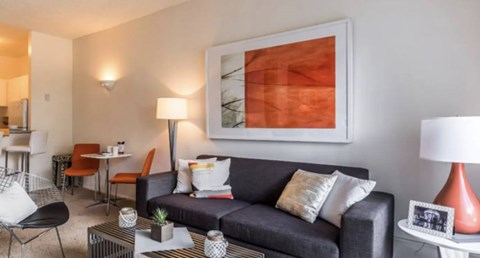 A living room with a grey couch, a coffee table, and a painting on the wall.