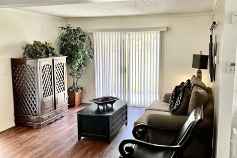A living room with a black couch and a wooden cabinet.