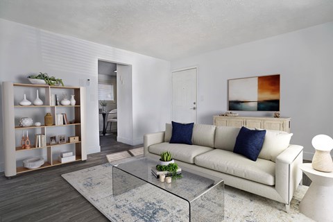 A modern living room with a white couch and a glass coffee table.
