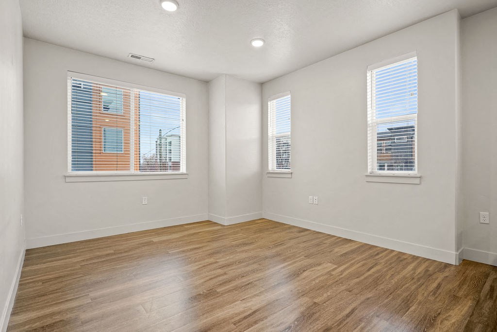 Empty room with wooden floors and two windows.