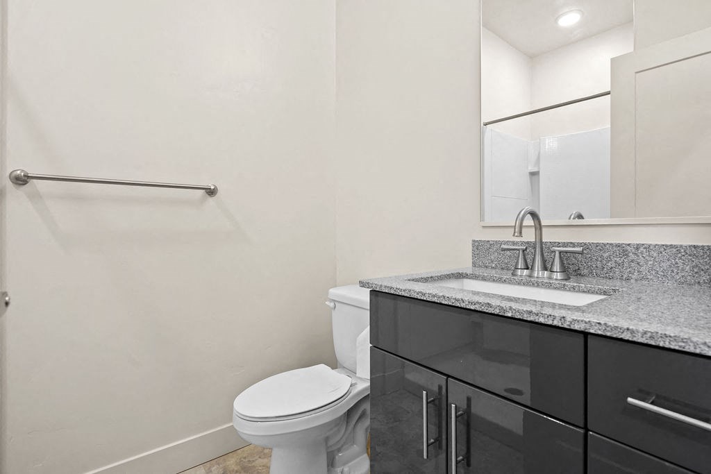 A bathroom with a toilet, sink, and mirror.