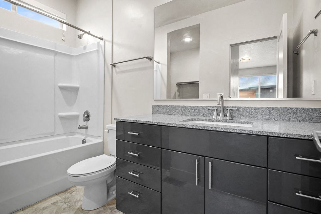 A modern bathroom with a white toilet and a black vanity.