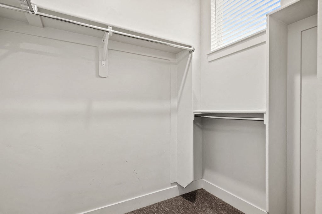 A white closet with a shelf and a white door.