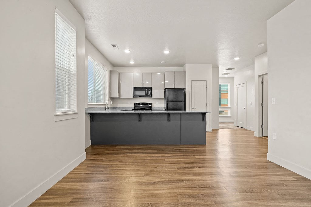 A kitchen with a wooden floor and white walls.