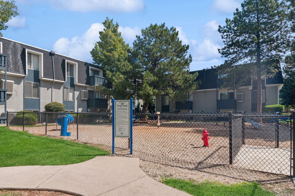 a fenced in dog park in front of an apartment building