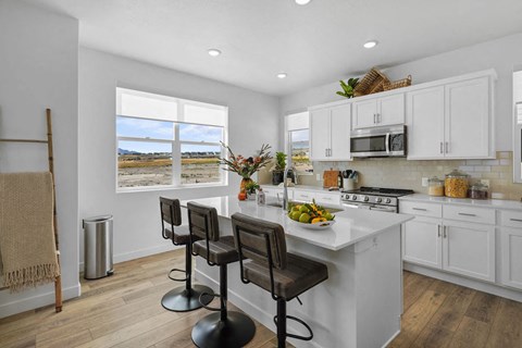 A kitchen with white cabinets and a large island with a bowl of fruit on it.