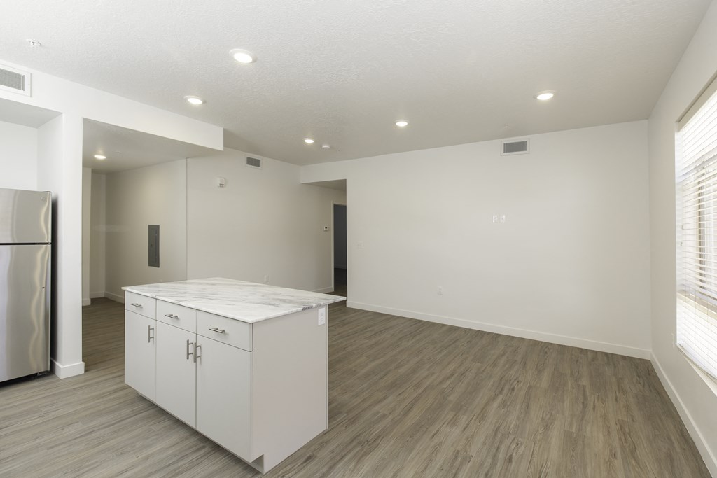 the living room and kitchen in a new home with white walls and wood flooring
