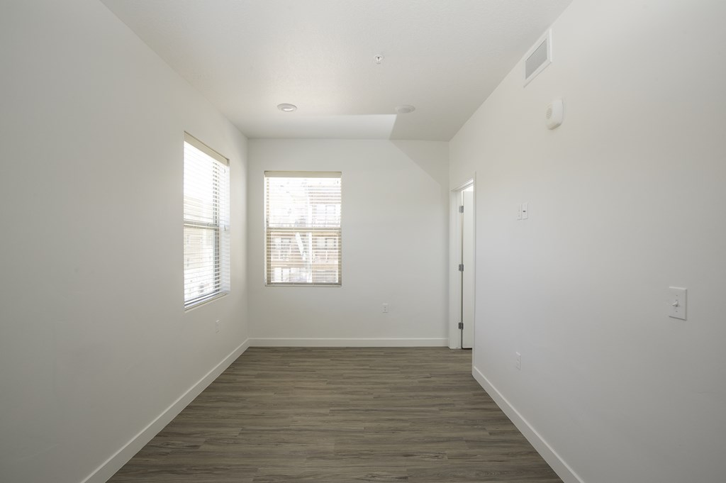 a bedroom with white walls and wood flooring and a window