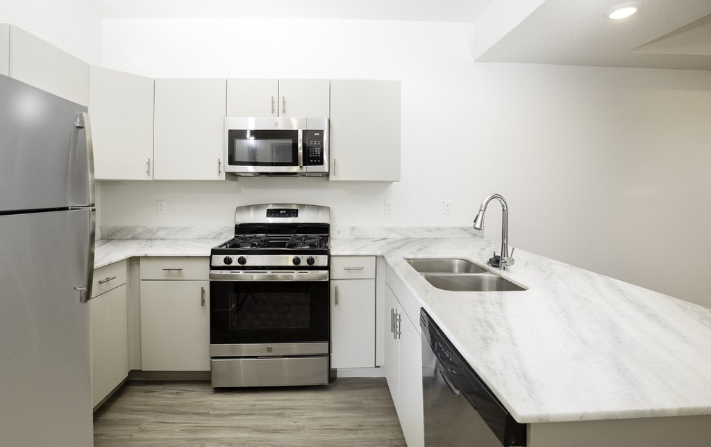a kitchen with white marble counter tops and stainless steel appliances