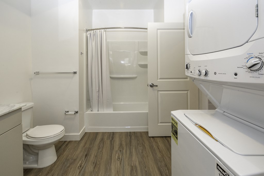 a bathroom with a washer and dryer and a shower and a toilet