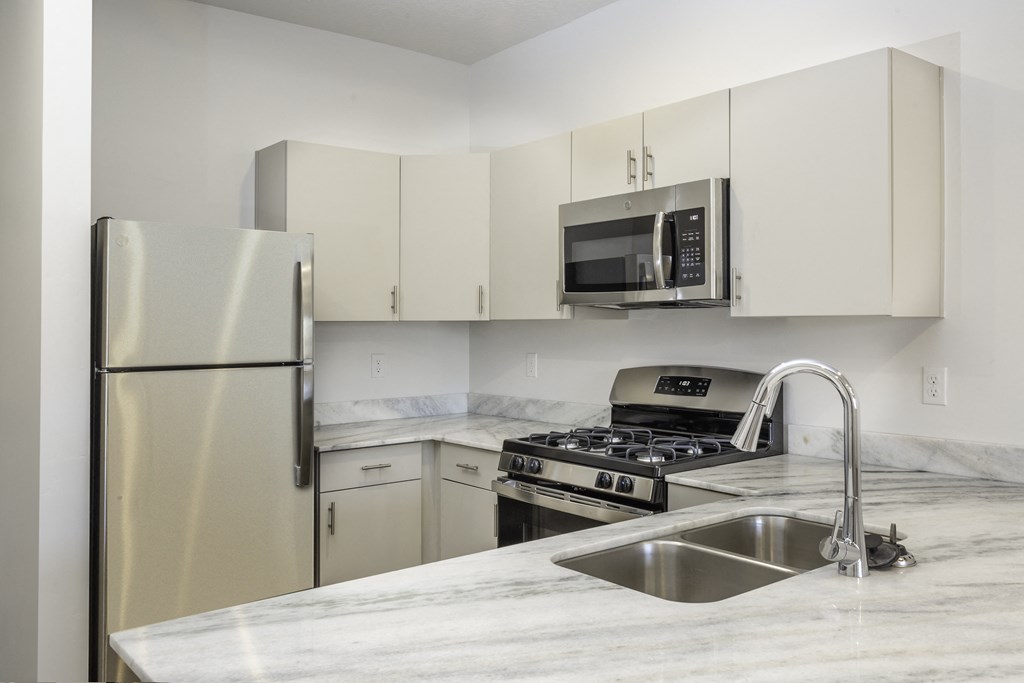 a kitchen with white cabinets and stainless steel appliances and a sink
