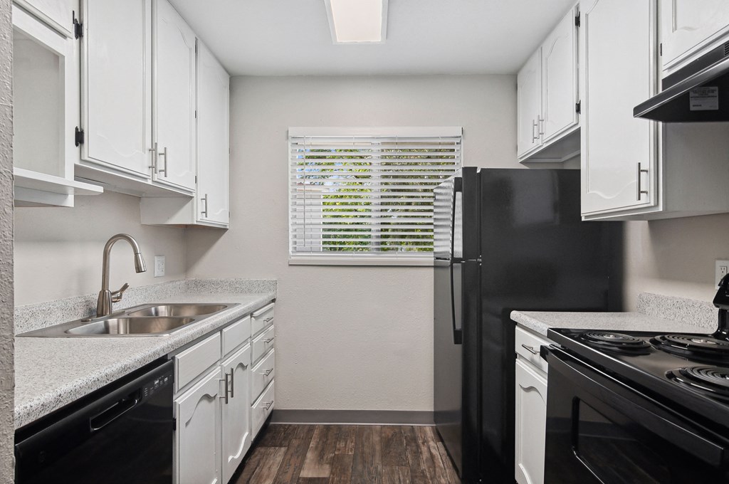 an empty kitchen with white cabinets and black appliances