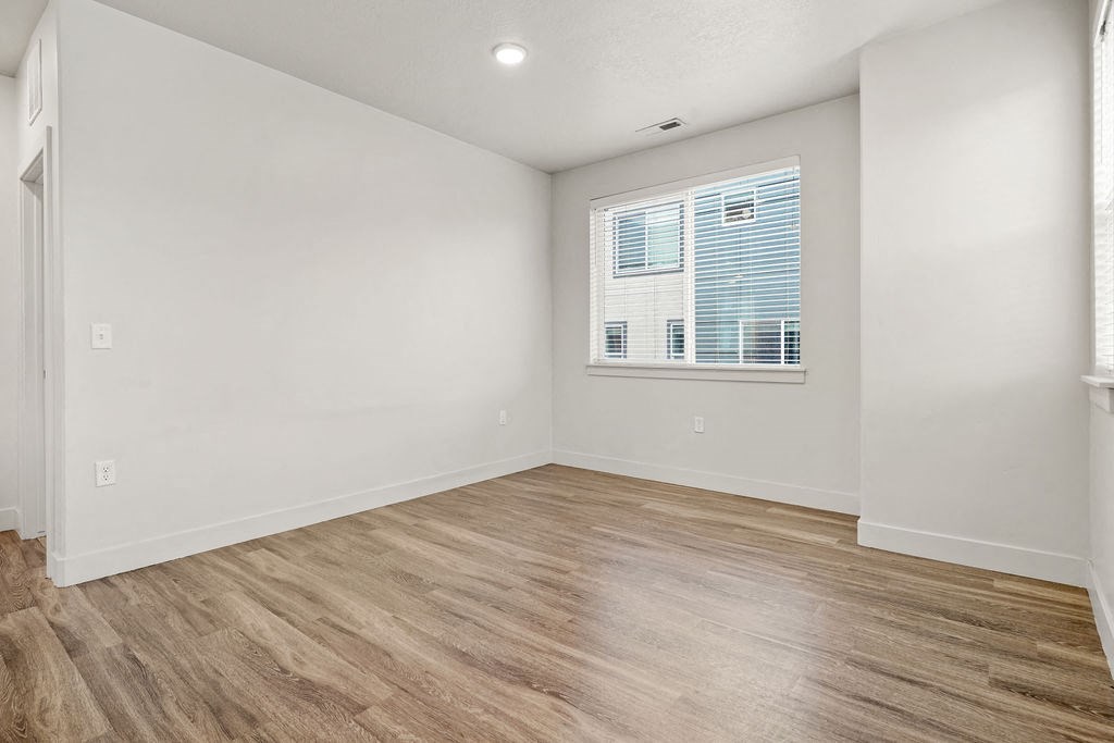 A room with wooden flooring and a window with blinds.