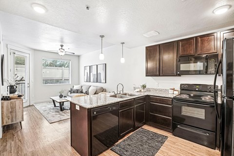 A kitchen with dark brown cabinets and black appliances.